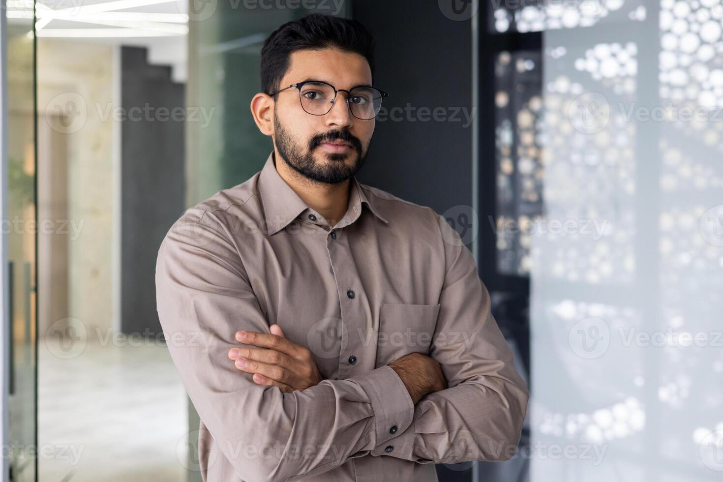 Porträt von ernst zuversichtlich Hindu Geschäftsmann, Mann im Hemd Denken und suchen beim Kamera mit gekreuzt Waffen, reifen Boss Arbeiten Innerhalb Büro beim Arbeitsplatz, Financier Buchhalter im Brille. foto