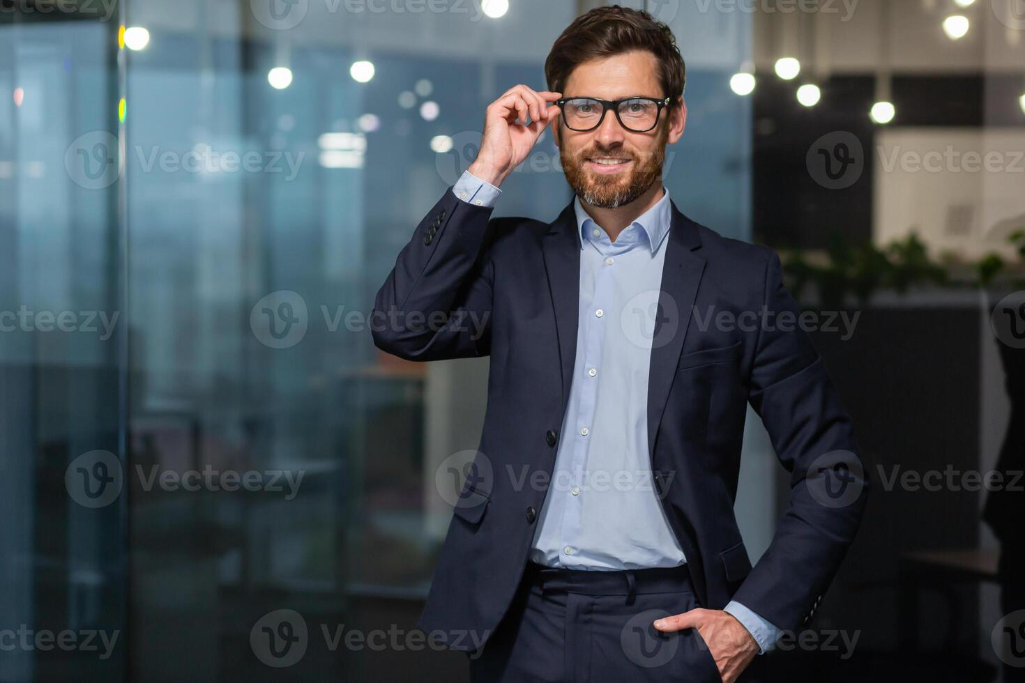 Porträt von erfolgreich reifen Chef, Senior Geschäftsmann im Brille und Geschäft passen suchen beim Kamera und lächelnd, Mann Arbeiten Innerhalb modern Büro Gebäude. foto