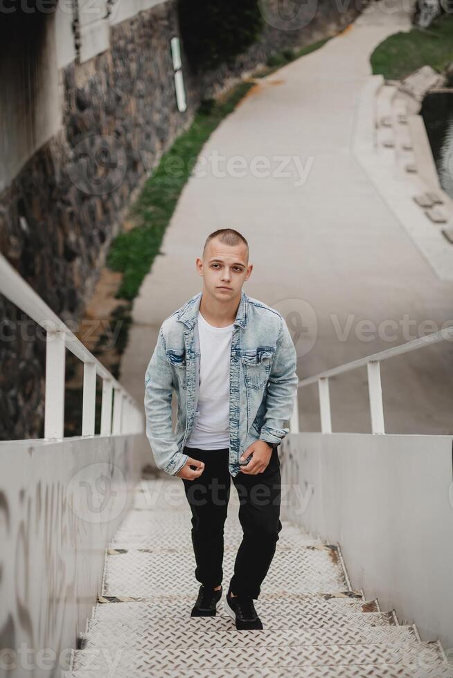 ein Mann im ein Denim Jacke und schwarz Hose ist Gehen oben ein einstellen von Treppe foto