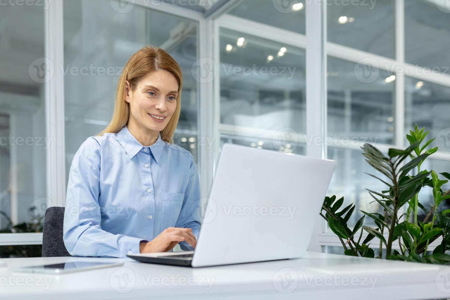 ein konzentriert Fachmann Frau engagiert mit ihr Laptop im ein hell, zeitgenössisch Büro Einstellung, verkörpern Effizienz und Einsatz. foto