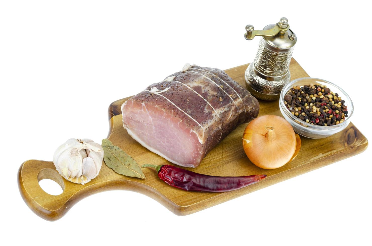Stück getrocknetes Schweinefleisch mit Gewürzen auf weißem Hintergrund. foto