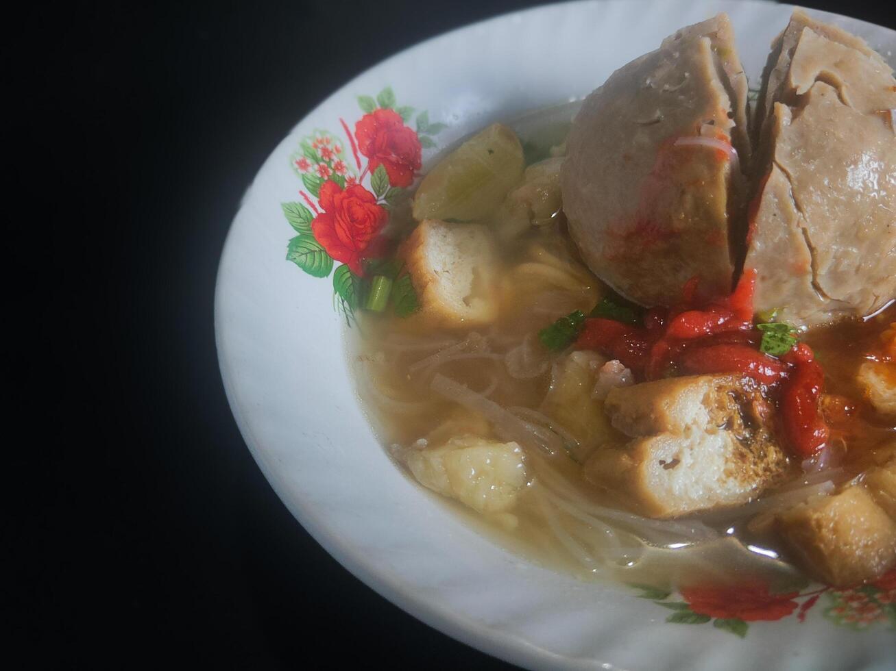 Fotografie von Jumbo Fleischklößchen Essen von Indonesien auf ein Schüssel auf ein schwarz Hintergrund foto