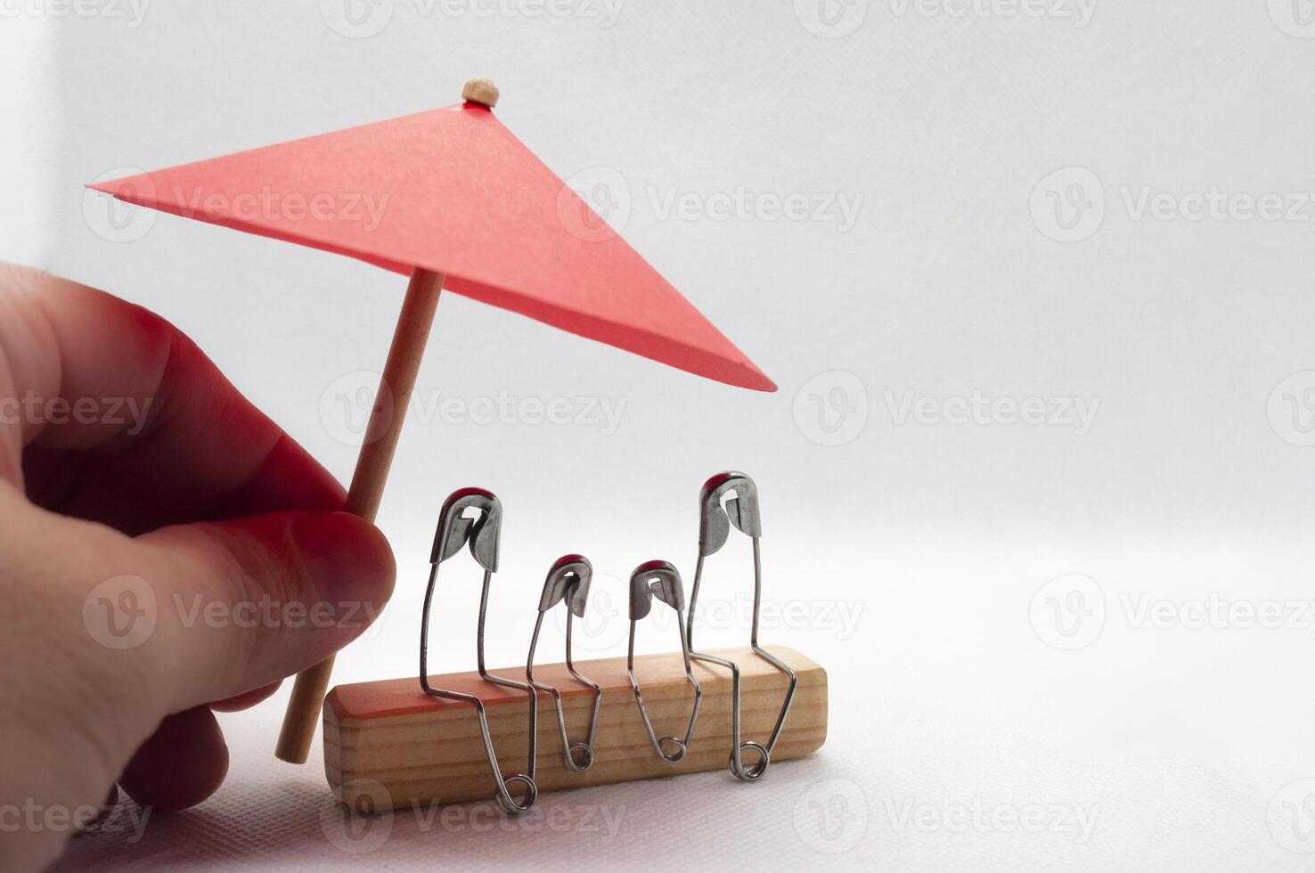 Modell- Sicherheit Stift von Familie Sitzung auf hölzern Block mit rot Regenschirm Hintergrund. Versicherung Konzept foto