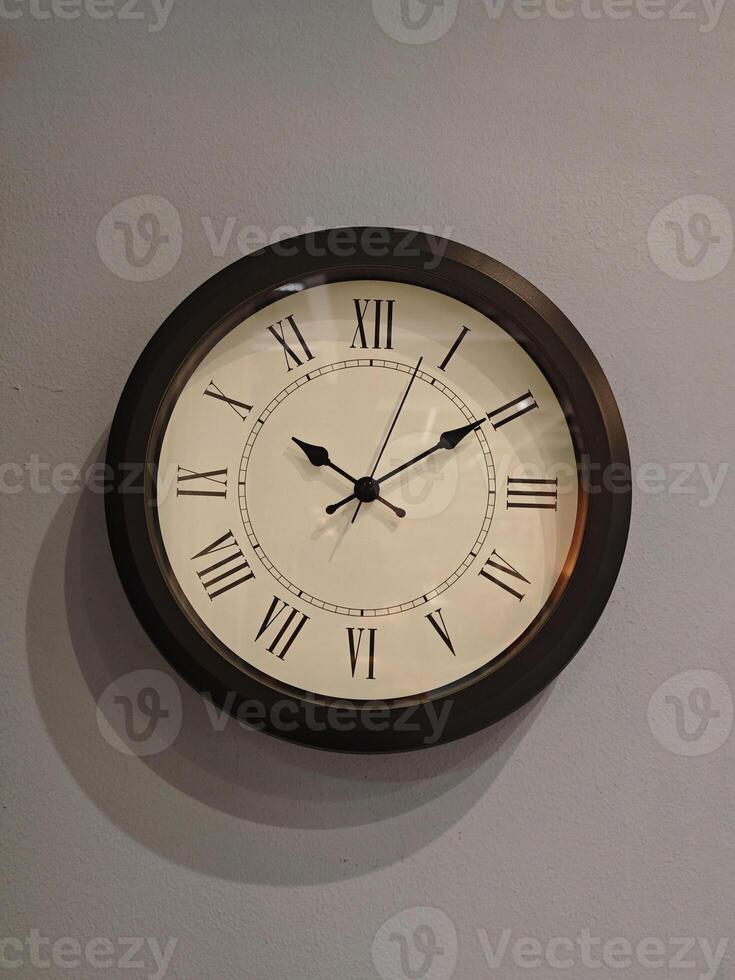 elegant Mauer Uhr mit römisch Ziffern auf subtil grau Hintergrund foto
