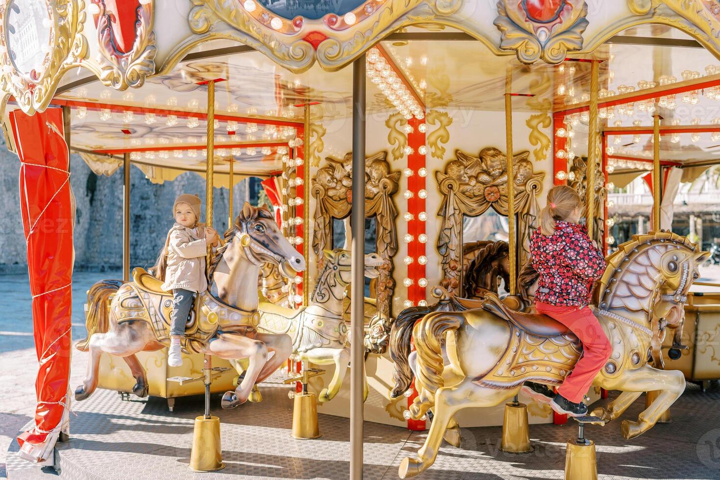 wenig Kinder Reiten bunt Spielzeug Pferde auf ein Karussell während halten auf zu ein Pole foto