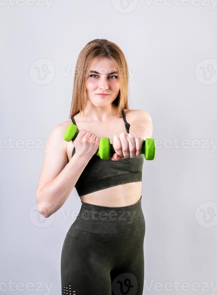junge sportliche Frau macht Übungen mit Hanteln isoliert auf grau foto