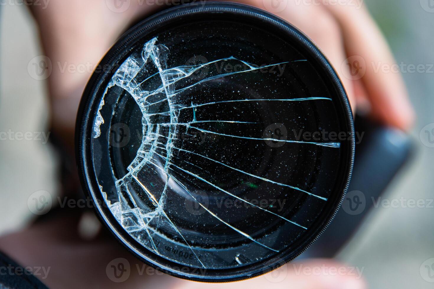 Hände von jung Fotograf halten dslr Foto Kamera mit gebrochen Linse Filter Glas nach wenn fallen Nieder auf zu das Boden. schließen hoch. zerstört geknackt Foto Filter. Makro. oben Sicht. selektiv Fokus.
