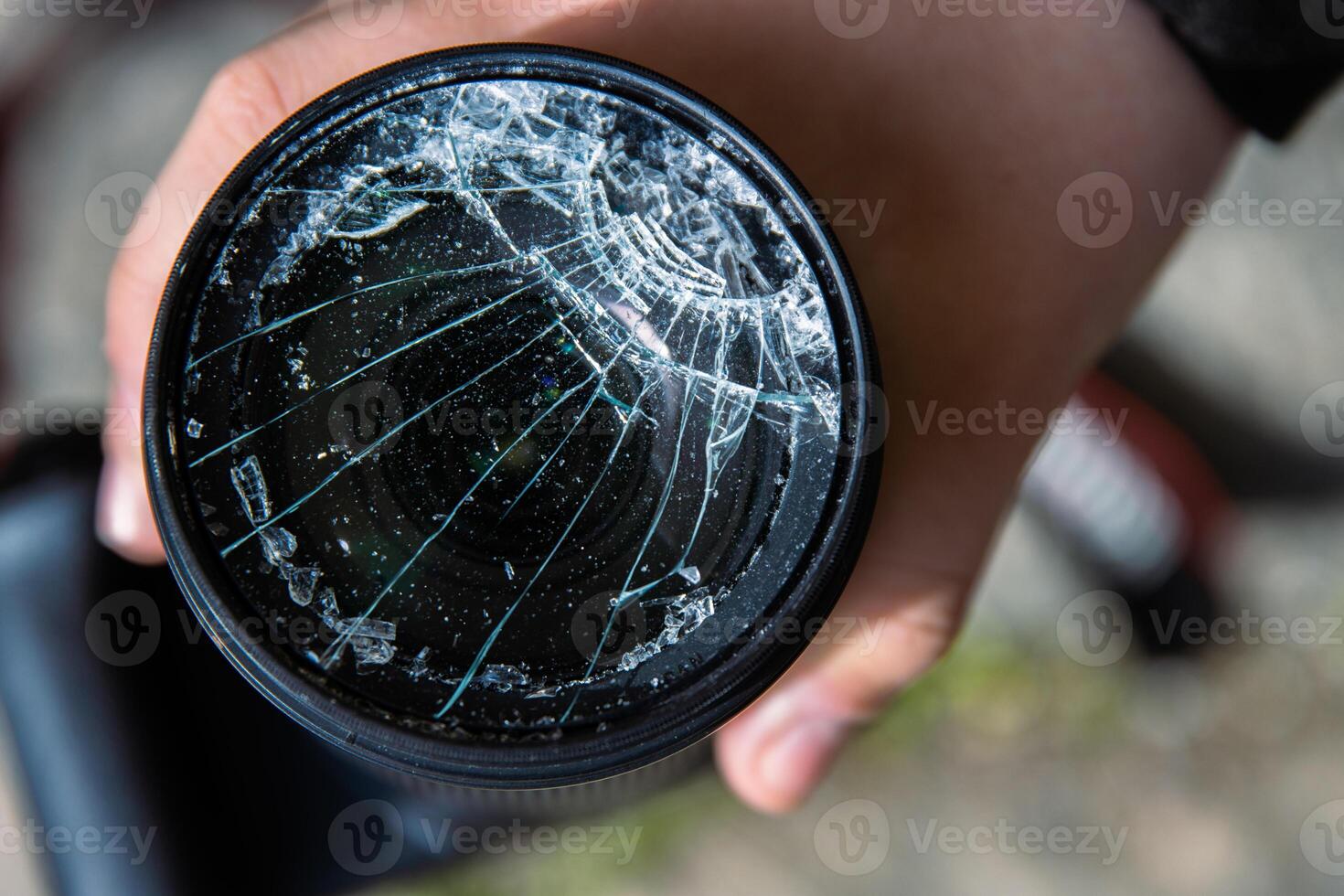 Hände von jung Fotograf halten dslr Foto Kamera mit gebrochen Linse Filter Glas nach wenn fallen Nieder auf zu das Boden. schließen hoch. zerstört geknackt Foto Filter. Makro. oben Sicht. selektiv Fokus.