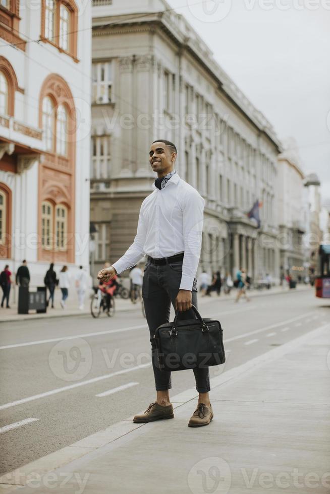 junger afroamerikanischer Geschäftsmann, der ein Taxi auf einer Straße wartet foto