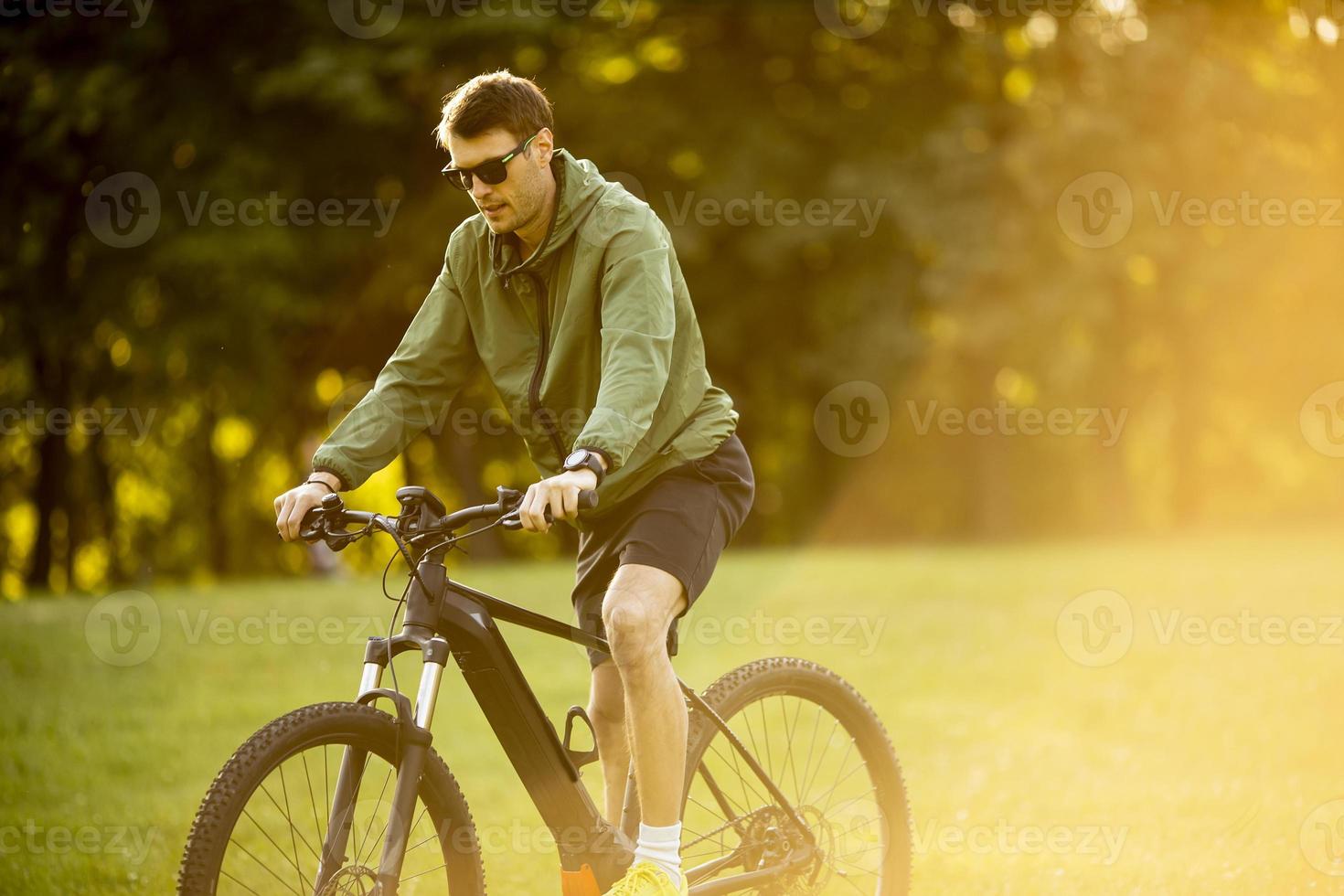 junger Mann, der im Park E-Bike fährt foto