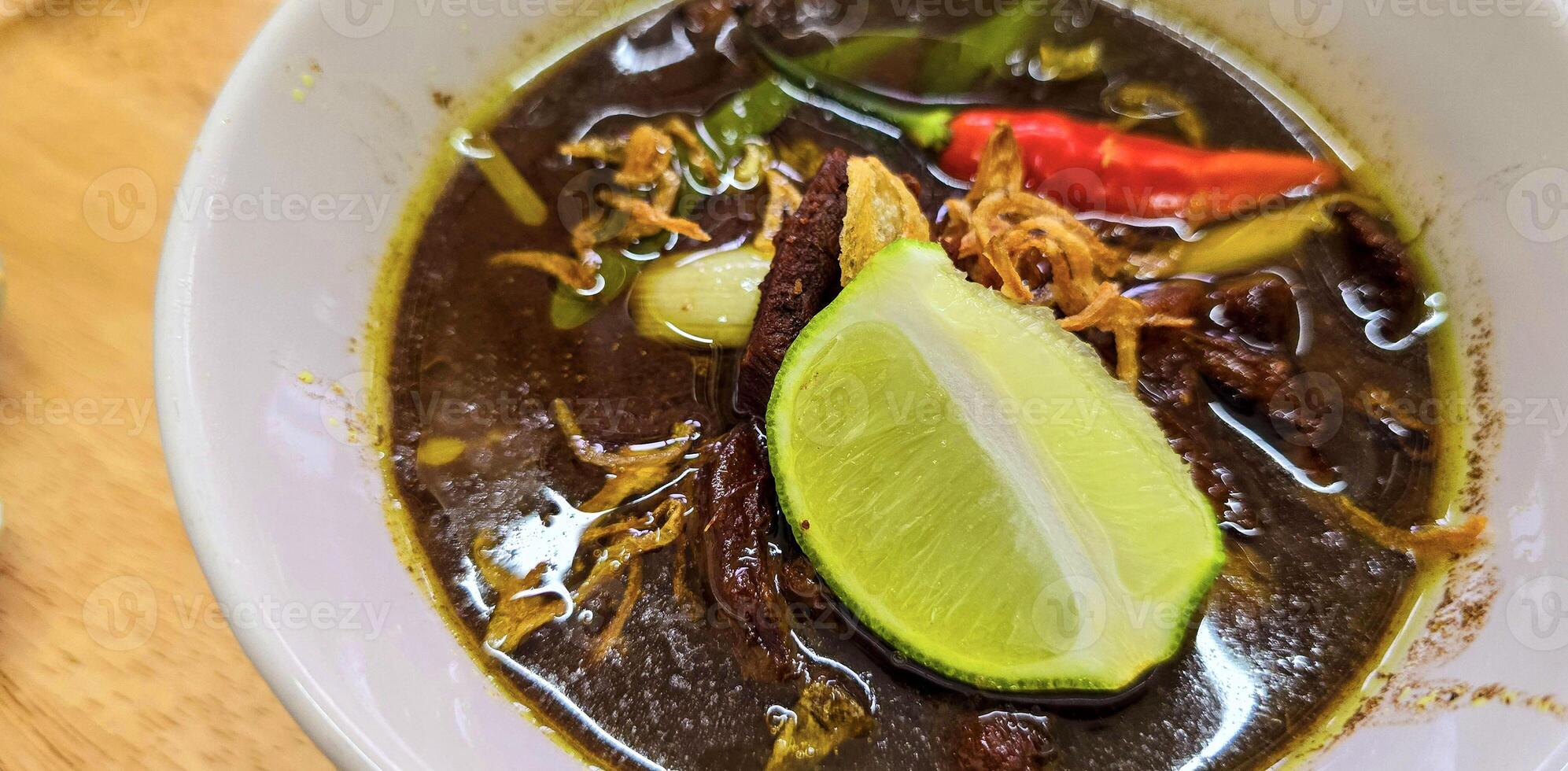 Rohon oder indonesisch schwarz Rindfleisch Suppe, schwarz Farbe sind von indonesisch Nuss namens Kluewek. serviert mit Kalk, Chili Paste, gesalzen Ei, und tempe Cracker. perfekt zum Rezept, Artikel, oder irgendein Kochen foto