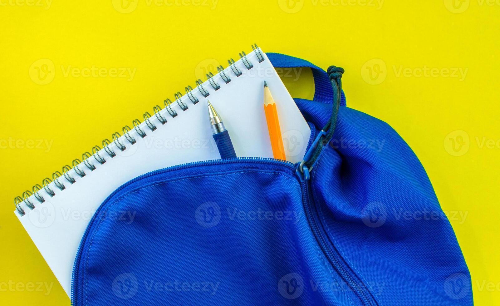 Schule Rucksack, Bleistift, Stift und Notizblock auf ein Gelb Hintergrund. foto