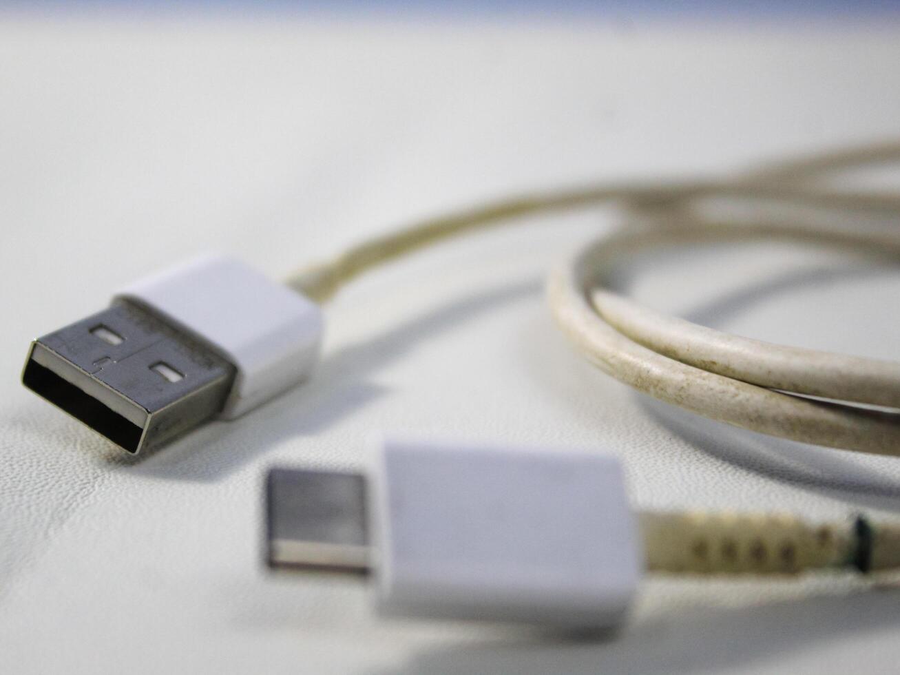 schließen oben das Weiß gebrochen Smartphone USB Kabel auf Weiß hölzern Hintergrund. foto