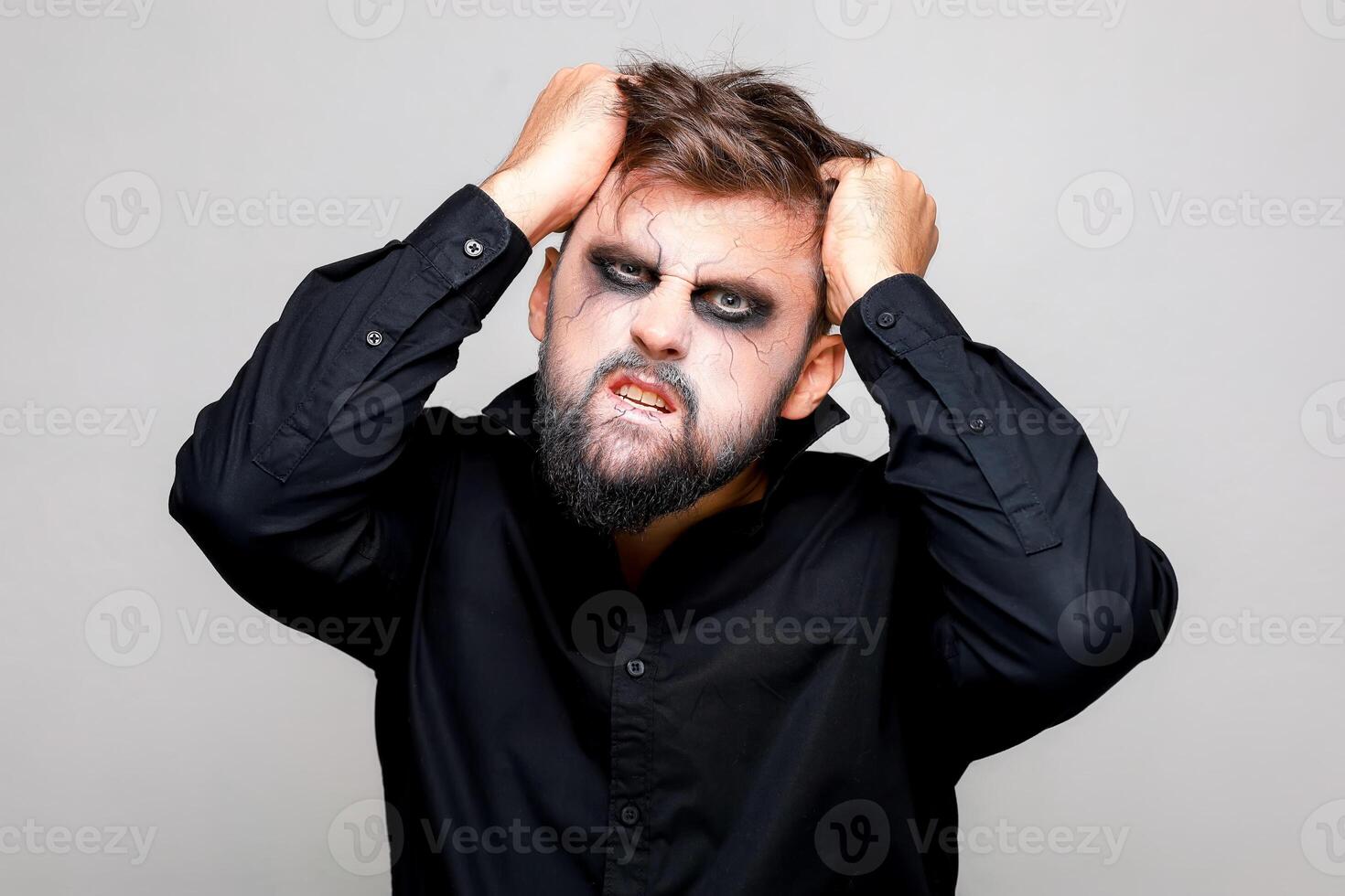 ein Mann mit ein Bart und bilden zum Halloween gepackt seine Haar mit seine Hände foto