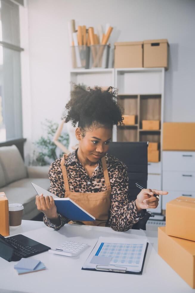 Startup-Kleinunternehmer oder freiberufliche Asiatin, die einen Laptop mit Box verwendet, junge Erfolgsasiatin mit erhobener Hand, Online-Marketing-Verpackungsbox und Lieferung, KMU-Konzept. foto