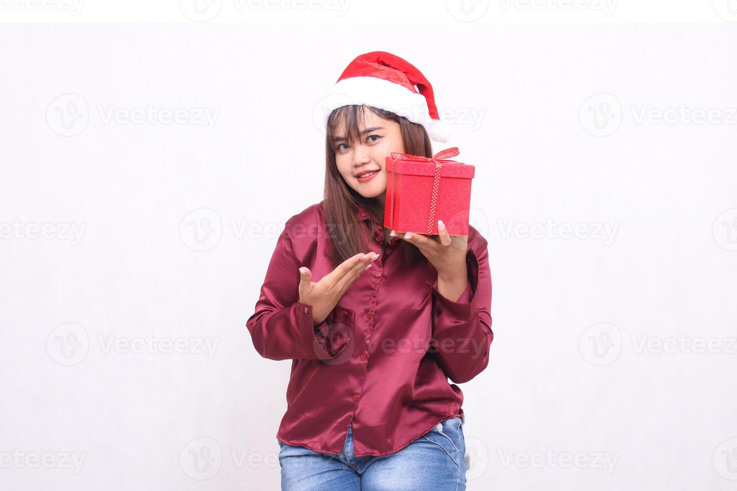 Foto Porträt von schön asiatisch Mädchen im ihr 20er Jahre Tragen Geschenk Box im Weihnachten Santa claus Hut modern glänzend rot Hemd Outfit vorstellen Box auf Weiß Hintergrund zum Beförderung und Werbung