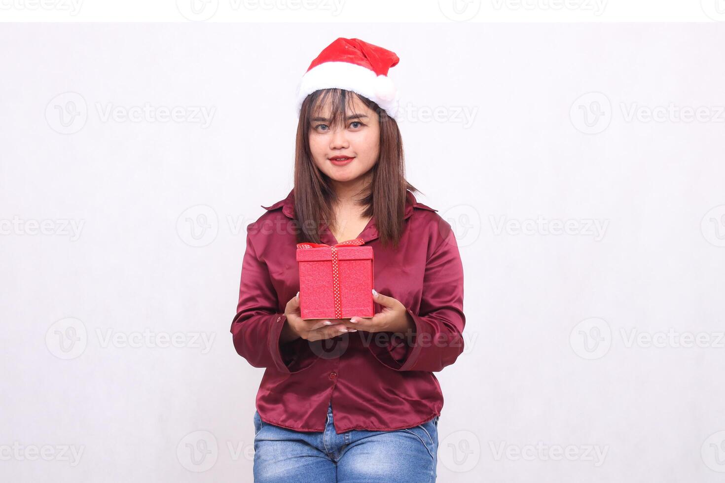 Foto Porträt von schön asiatisch Mädchen im ihr 20er Jahre Tragen verpackt Geschenke im Weihnachten Santa claus Hut modern glänzend rot Hemd Outfit gesehen auf Weiß Hintergrund zum Beförderung und Werbung