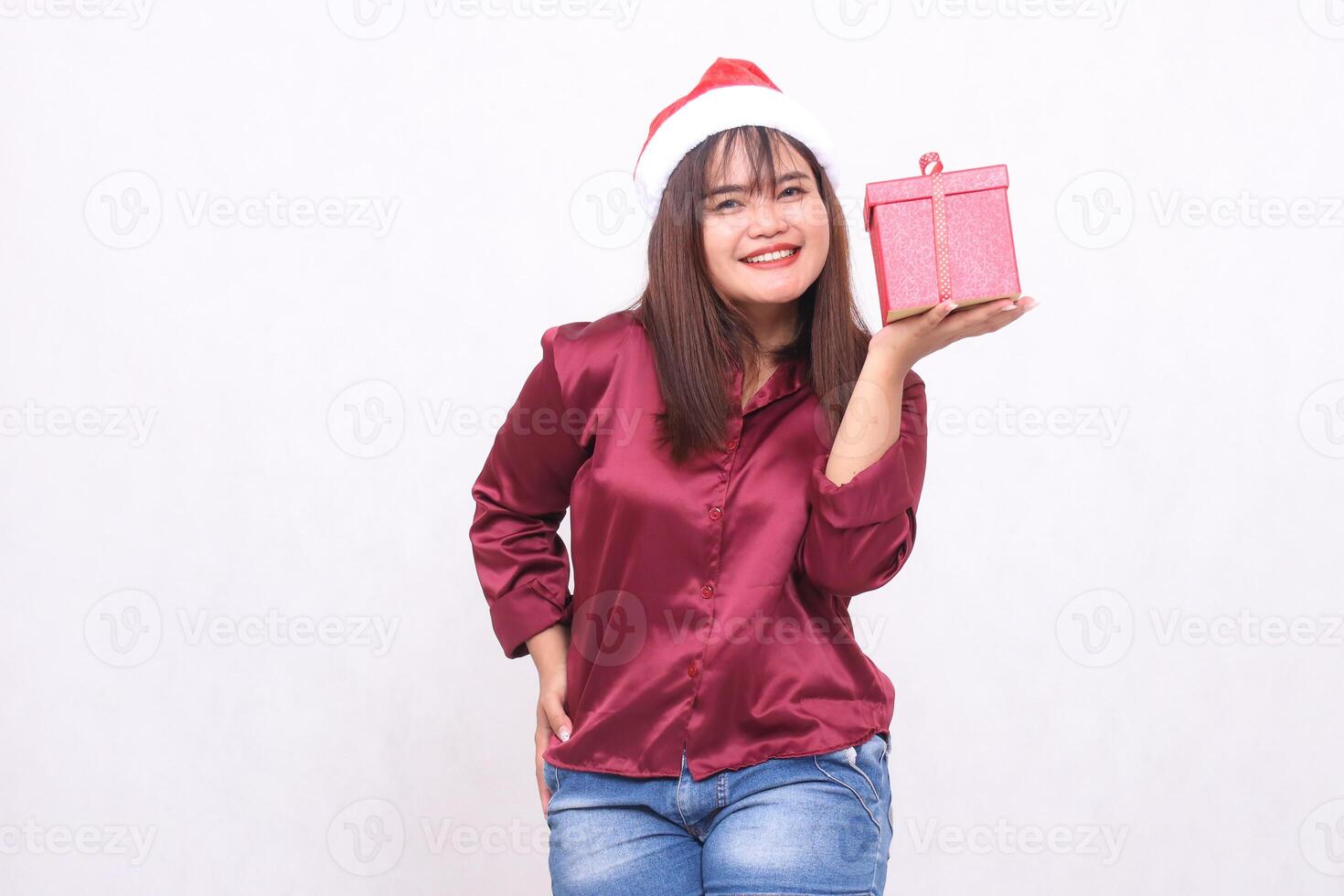 Porträt Foto von schön heiter alt asiatisch Mädchen Tragen Geschenk Box im Weihnachten Santa claus Hut modern glänzend rot Hemd Outfit links Hand Heben Box auf Weiß Hintergrund zum Beförderung ,Werbung