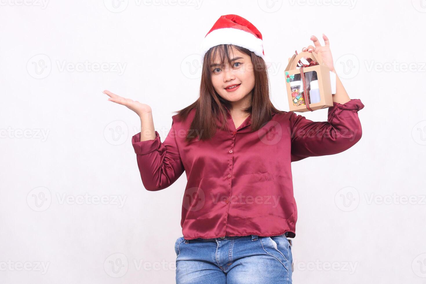 schön jung Frau Süd-Ost asiatisch lächelnd links Hand angehoben zu Geschenk Korb beim Weihnachten tragen Santa claus Hut modern rot Hemd Outfit Weiß Hintergrund zum Beförderung und Werbung foto