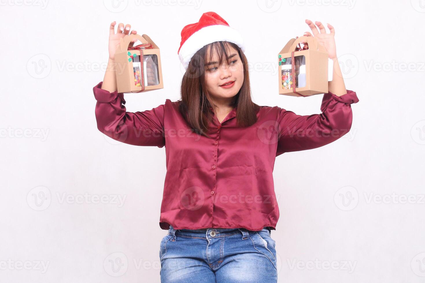 schön jung Süd-Ost asiatisch Frau lächelnd suchen beim Box Tragen 2 Kisten von Korb Geschenke beim Weihnachten tragen Santa Hut modern rot Hemd Outfit Weiß Hintergrund zum Beförderung und Werbung foto