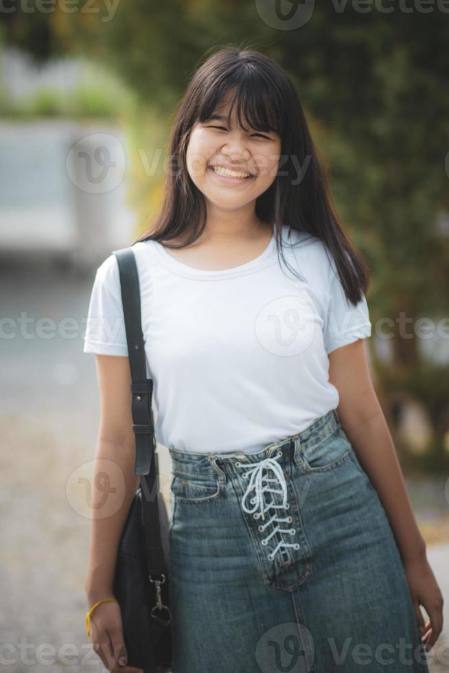 Fröhlicher asiatischer Teenager, der sich im öffentlichen Park entspannt foto