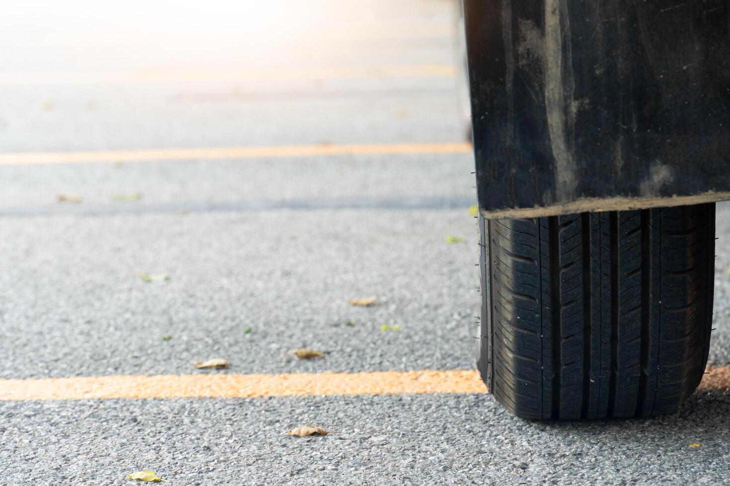 schließen von benutzt Auto Reifen auf Asphalt Straße mit Sonne Licht im das Morgen Zeit. mit Gelb Linie über das Boden. foto