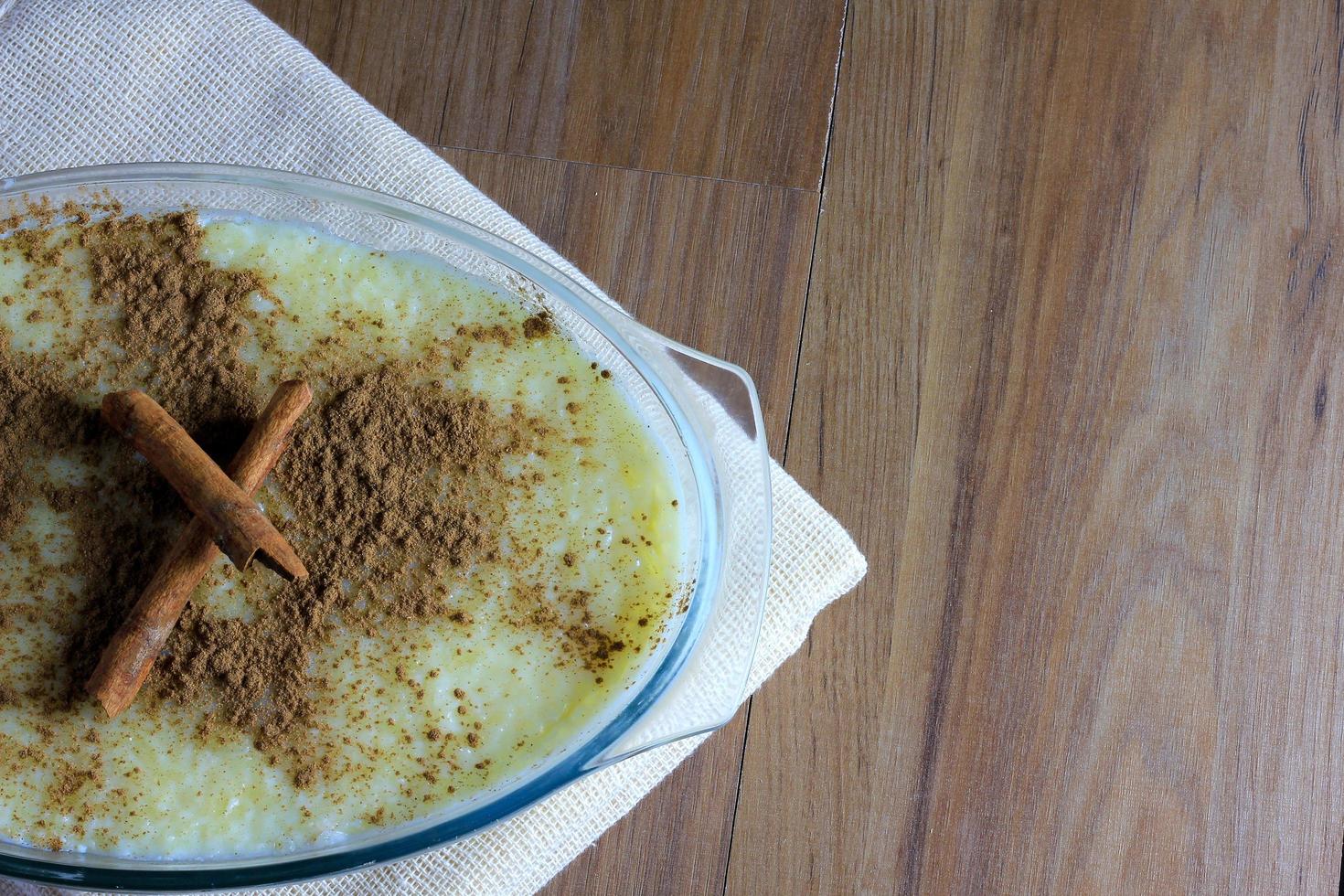 Milchreis mit Zimt auf Holztisch, auf Stoff gelehnt foto