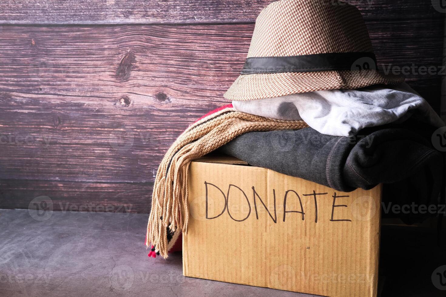 Spendenbox mit Spendenkleidung auf einem Holztisch. foto