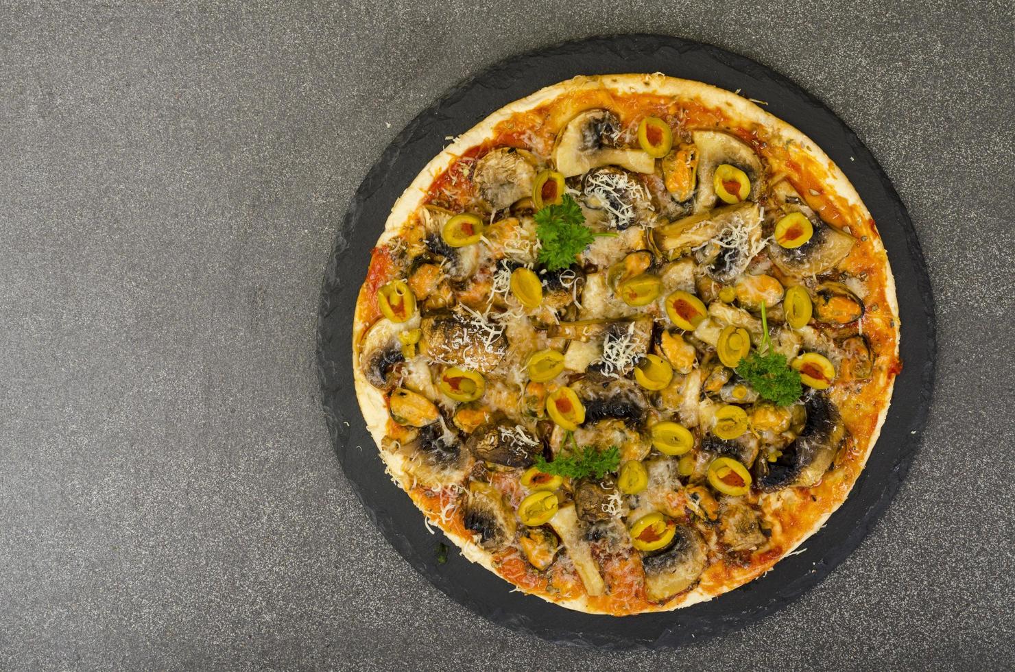 Pizza mit Muscheln, Pilzen, grünen Oliven. Studiofoto foto