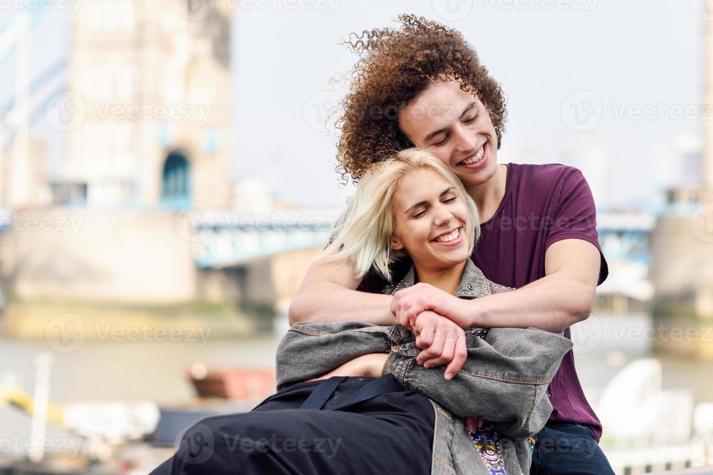 glückliches Paar, das sich an der Tower Bridge umarmt foto