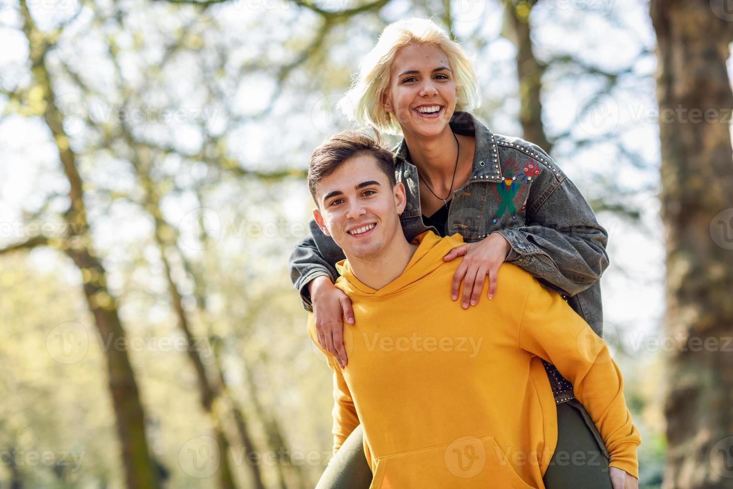 lustiges Paar in einem Stadtpark. Freund, der seine Freundin auf Huckepack trägt. foto