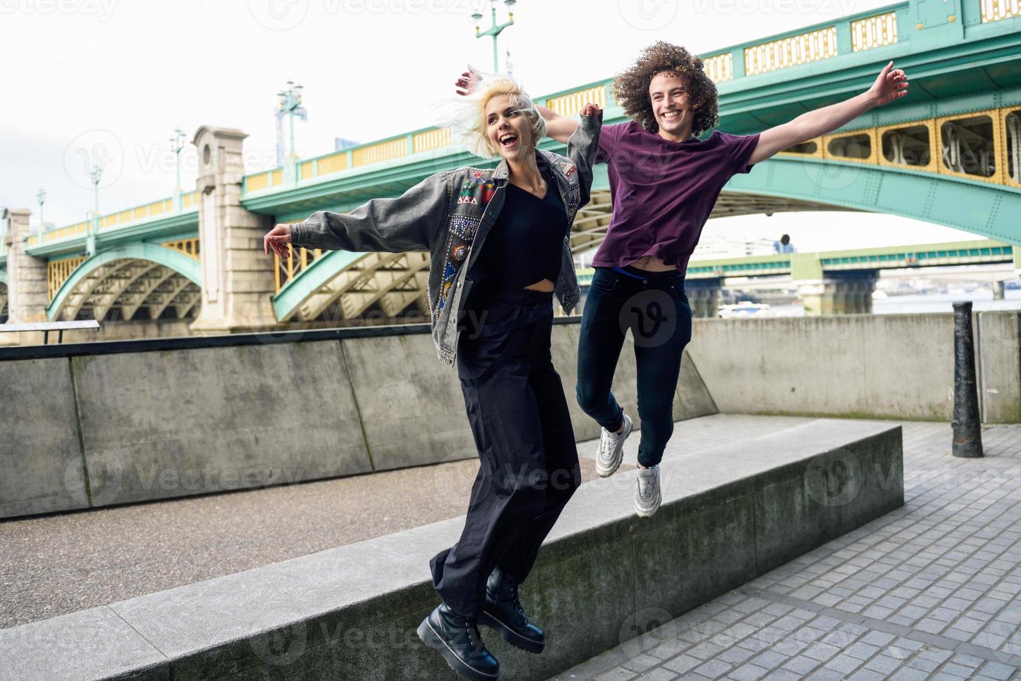 Lustiges Paar junping in der Nähe der Southwark Bridge über die Themse, London foto