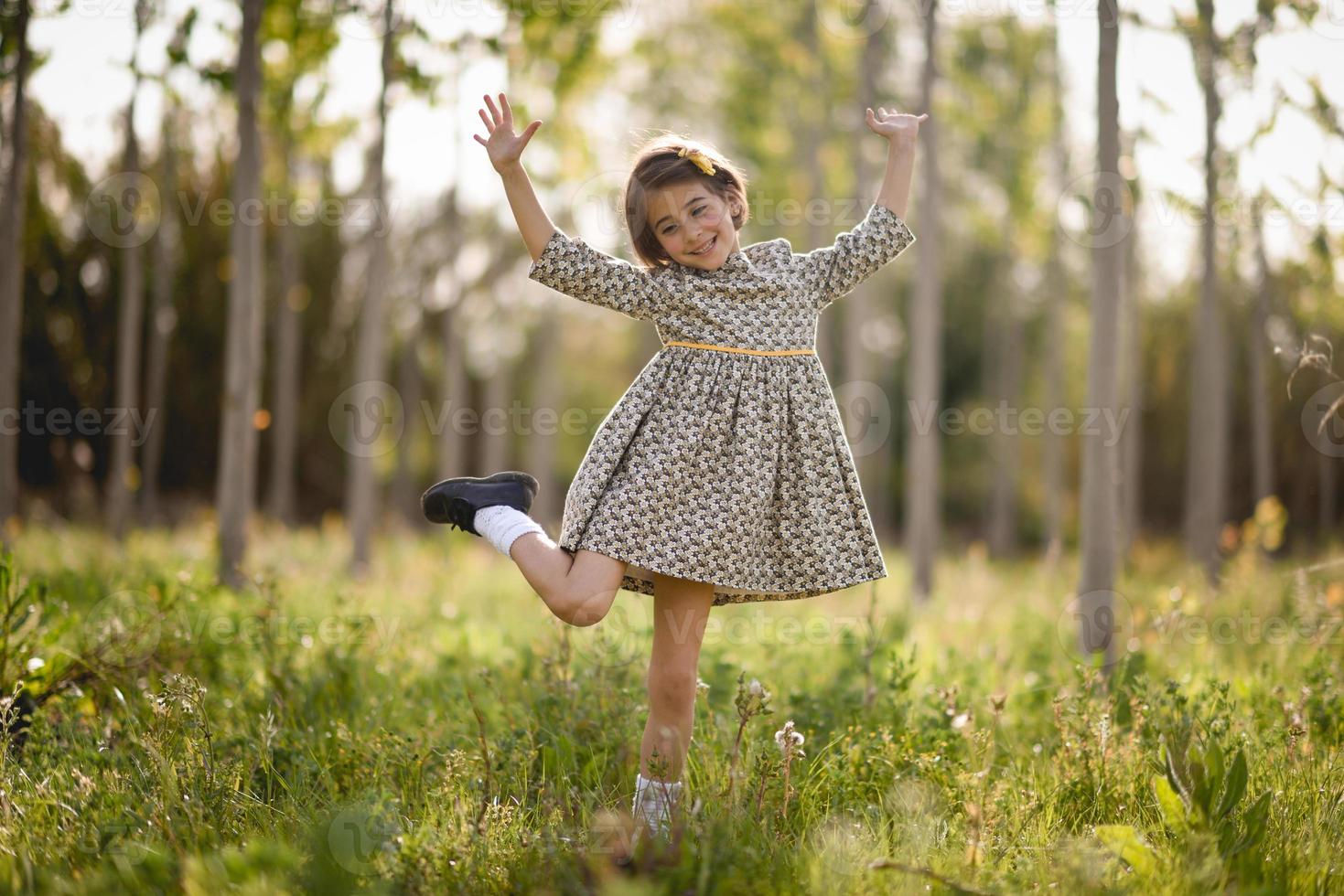 kleines Mädchen im Naturfeld, das ein schönes Kleid trägt foto