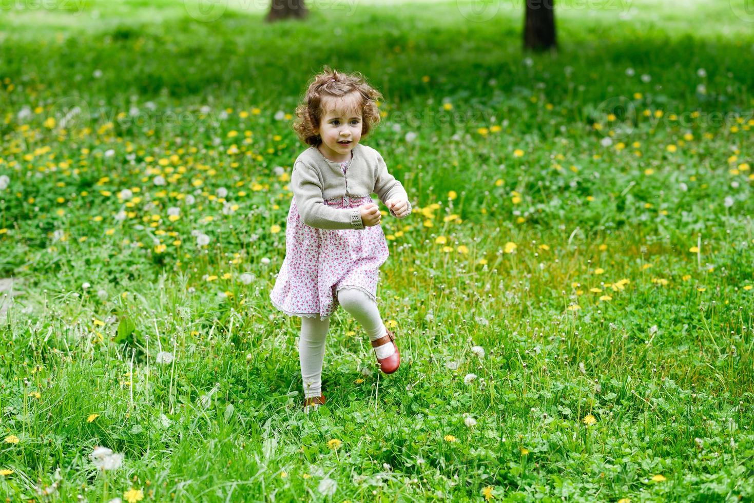 kleines Mädchen, das im Park läuft und spielt foto