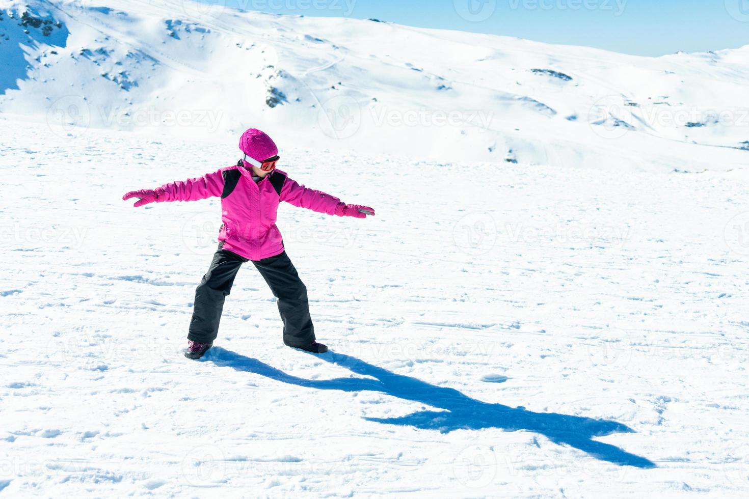 kleines Mädchen, das Snowboardtrainer auf Schnee spielt foto