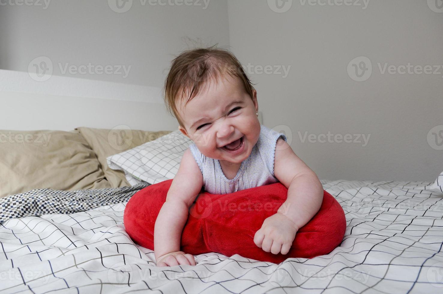 Baby liegt auf dem Bett ihrer Eltern mit lustigem Ausdruck foto