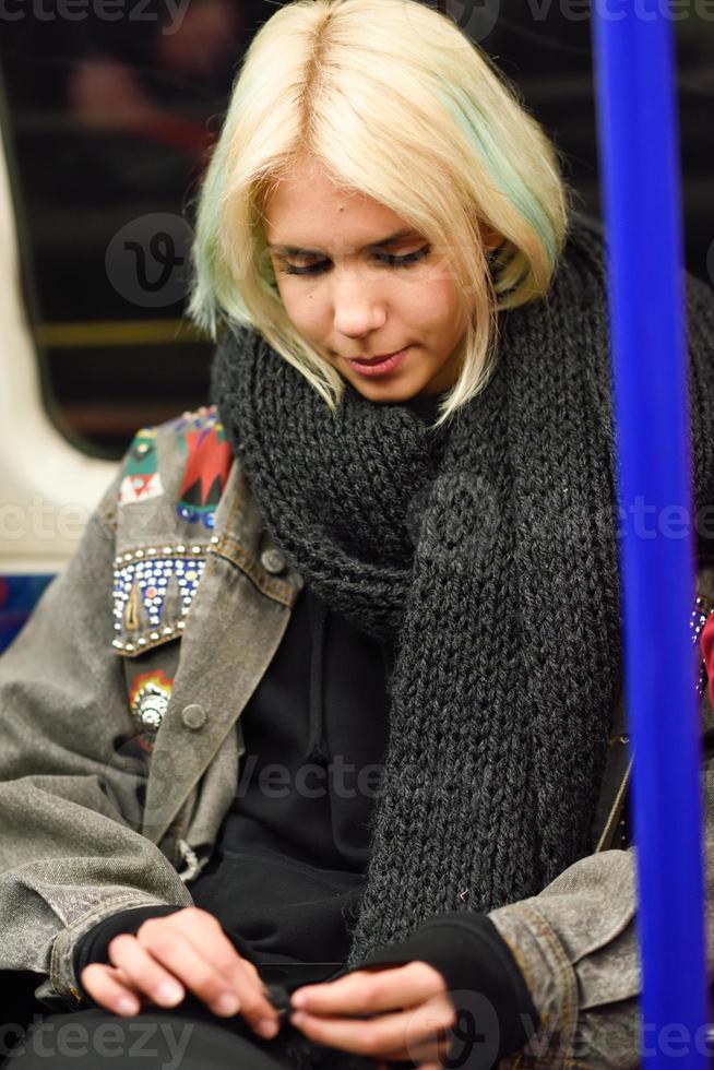 junge Frau mit kurzen Haaren, die in einem U-Bahn-Wagen sitzt foto