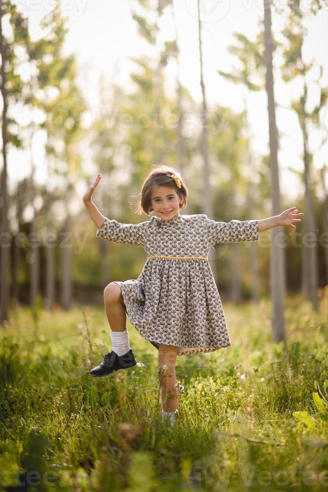 kleines Mädchen im Naturfeld, das ein schönes Kleid trägt foto