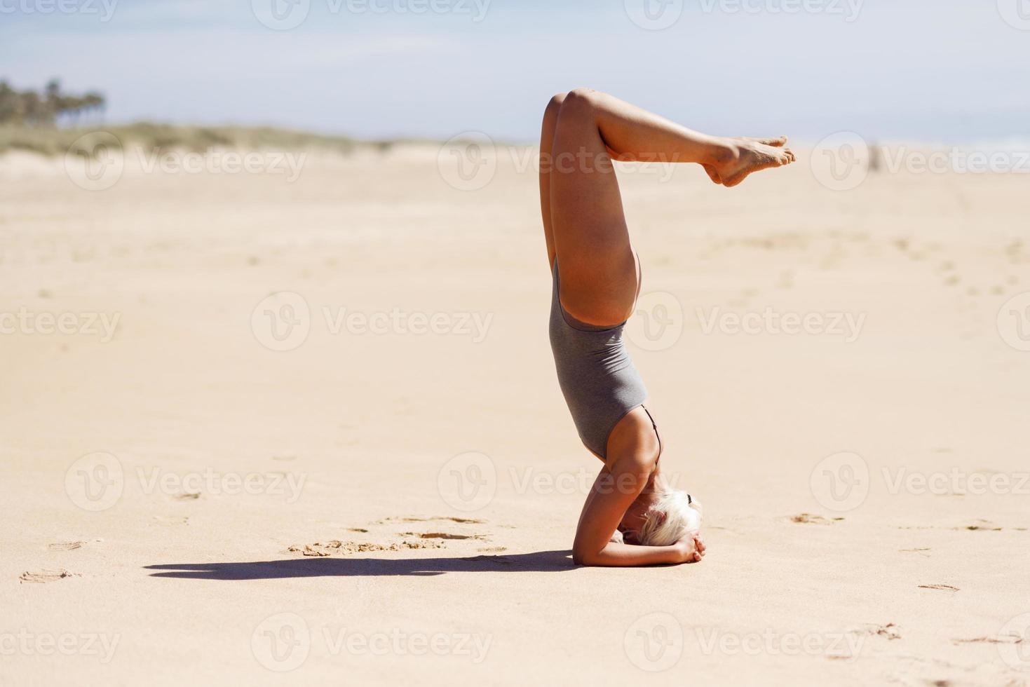 Kaukasische blonde Frau, die Yoga am Strand praktiziert foto