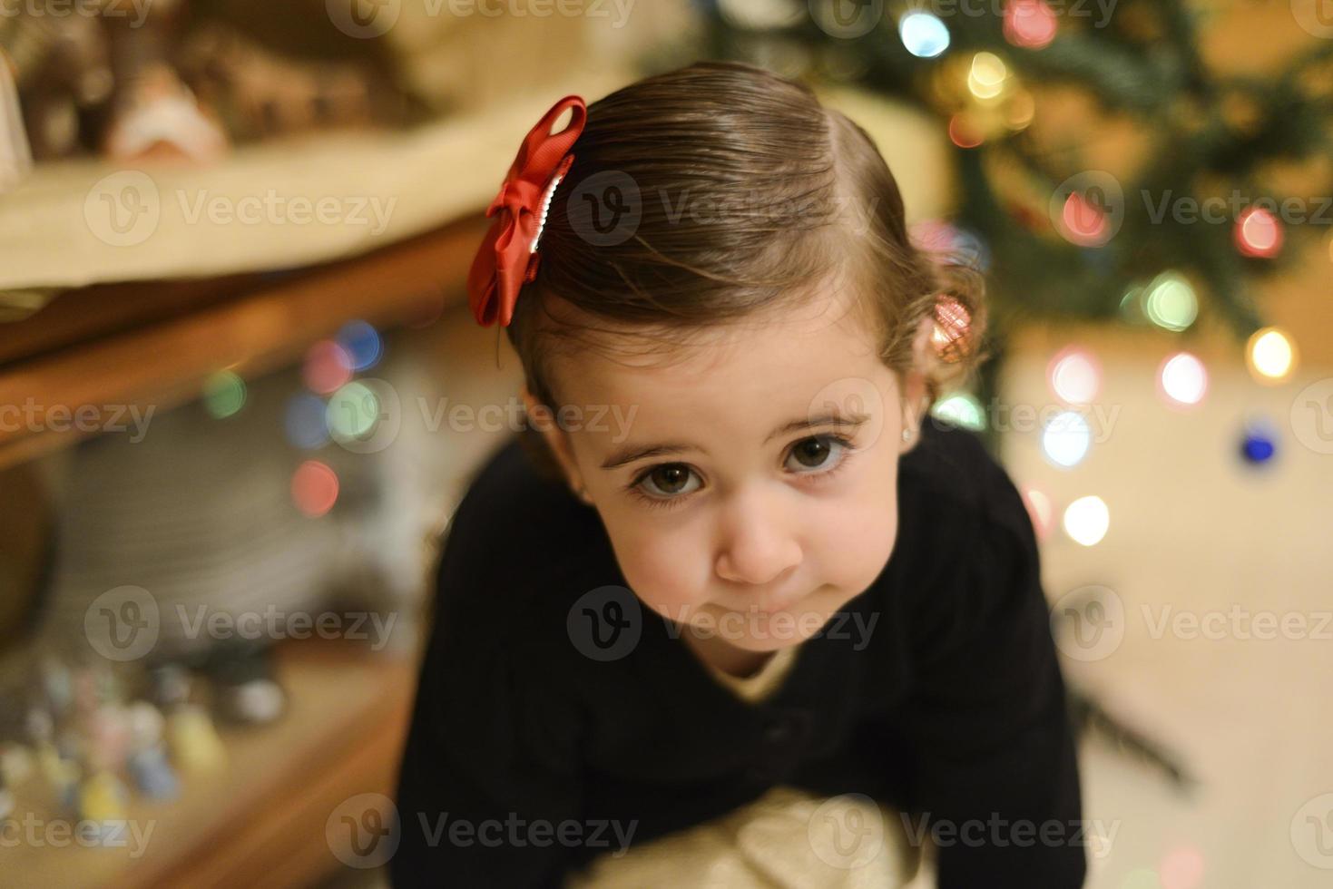 kleines Mädchen zu Hause mit Dekoration und defokussierten Weihnachtslichtern foto