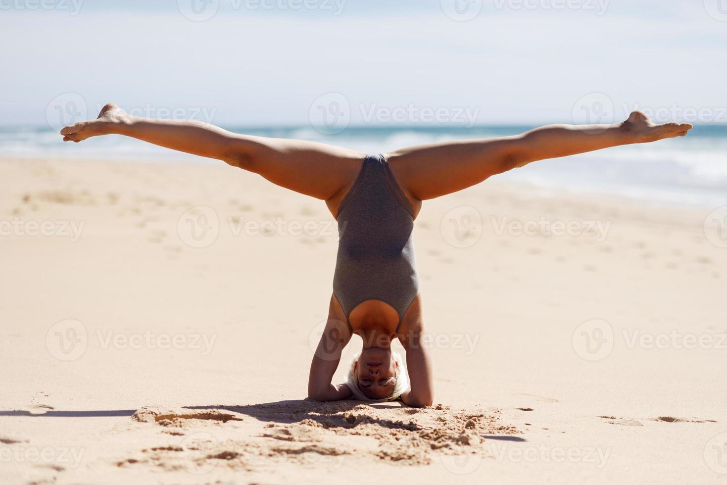 Kaukasische blonde Frau, die Yoga am Strand praktiziert foto