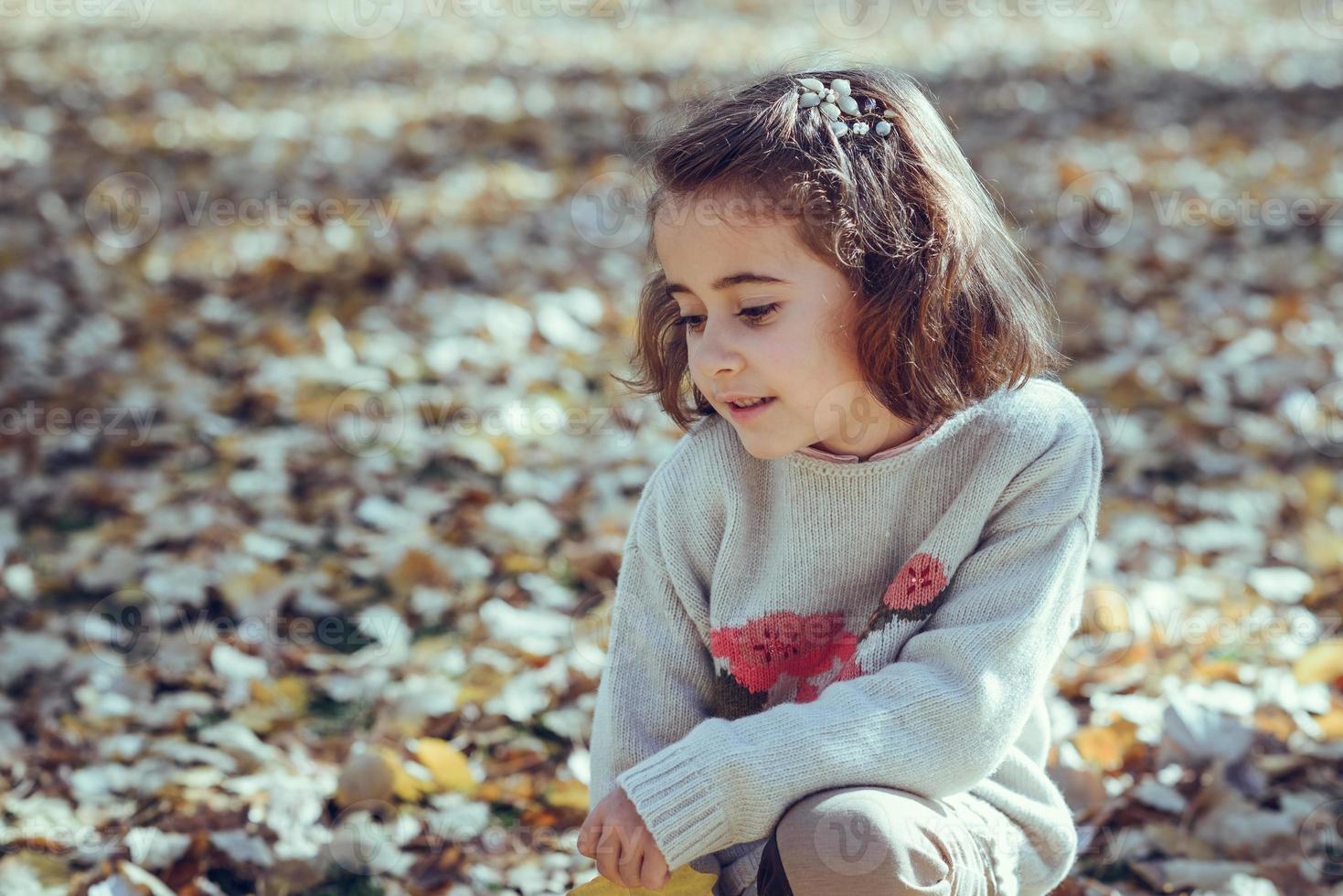 kleines Mädchen, das im Herbst in einem Stadtpark spielt foto