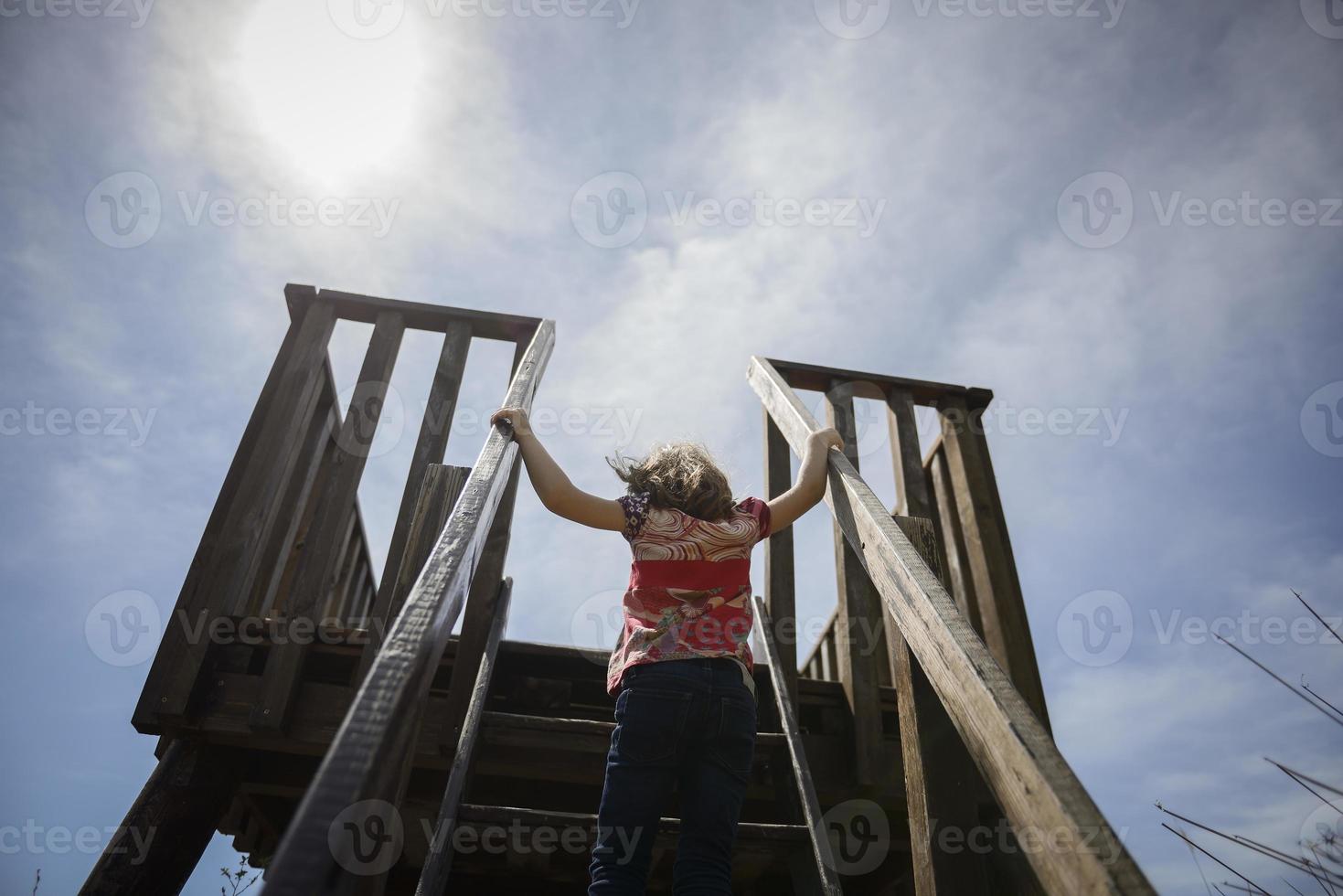 kleines Mädchen klettert auf einen hölzernen Aussichtsturm in einem Feuchtgebiet foto