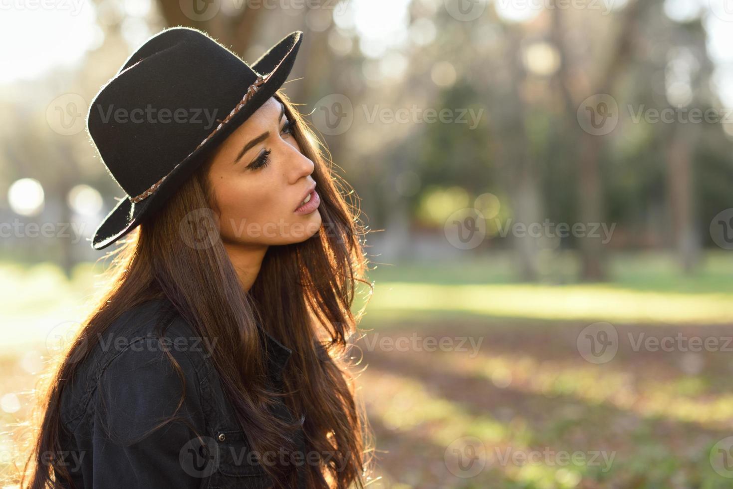 nachdenkliche Frau, die allein im Freien sitzt und Hut trägt foto
