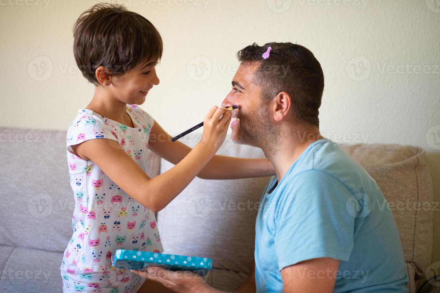 kleine süße Tochter, die ihren Vater schminkt foto