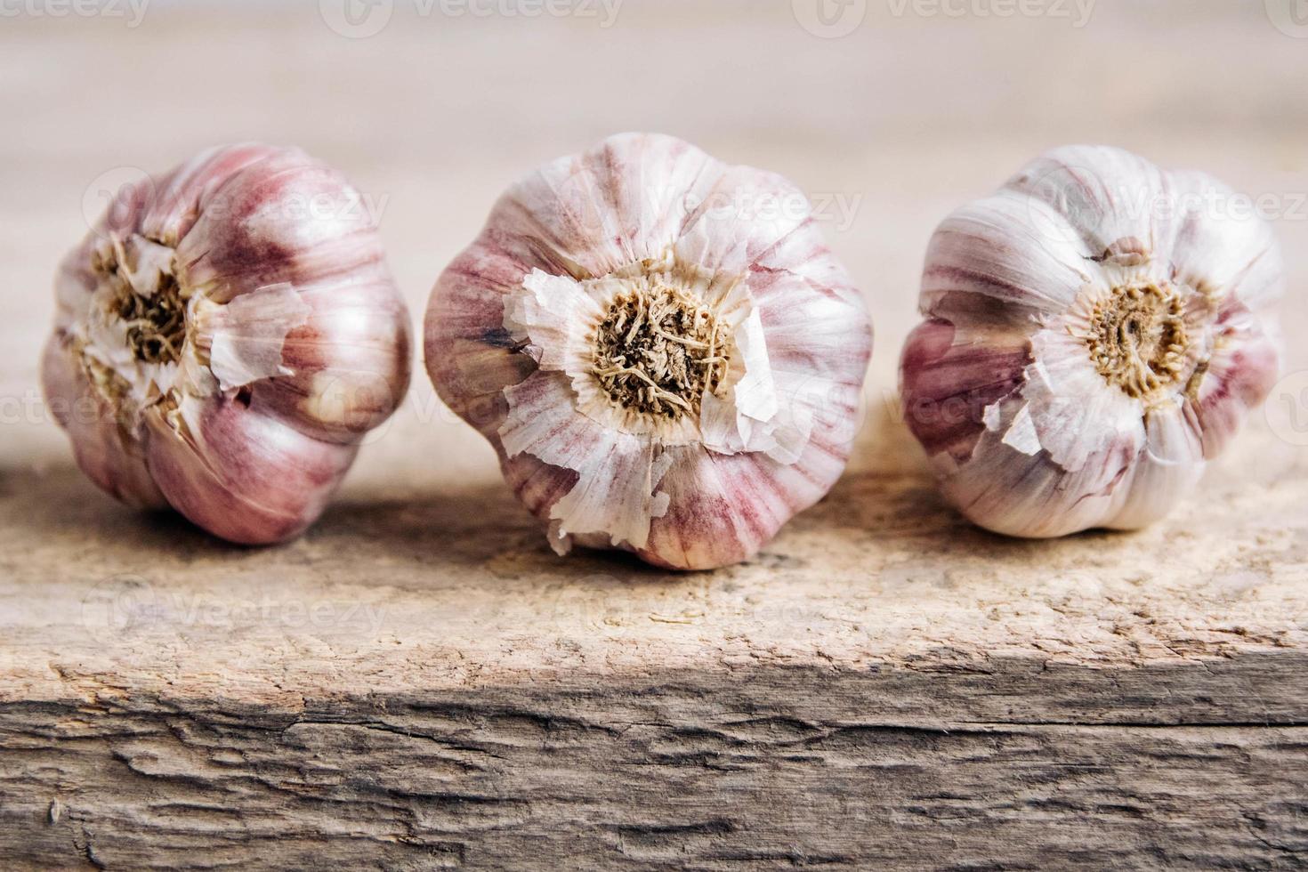 Knoblauch liegen in einer Reihe auf einem rustikalen Holzhintergrund foto