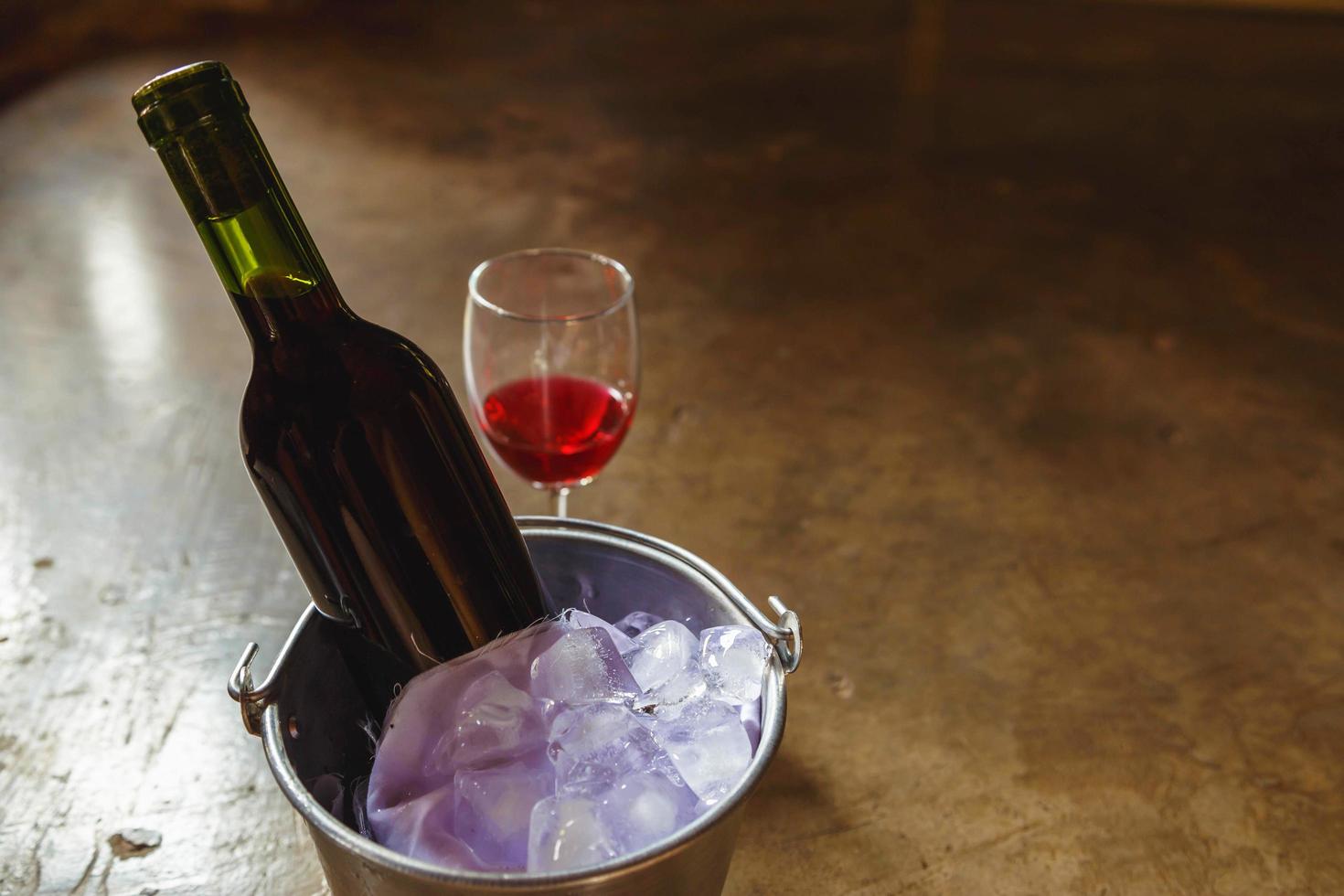 Flasche Rotwein im Eiskübel und ein Glas Rotwein foto