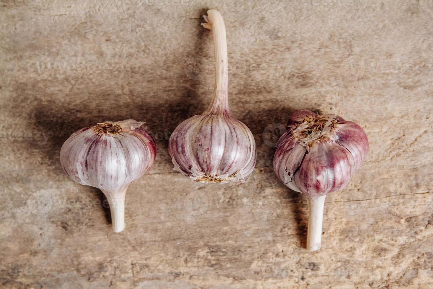 Knoblauch liegen in einer Reihe auf einem rustikalen Holzhintergrund foto