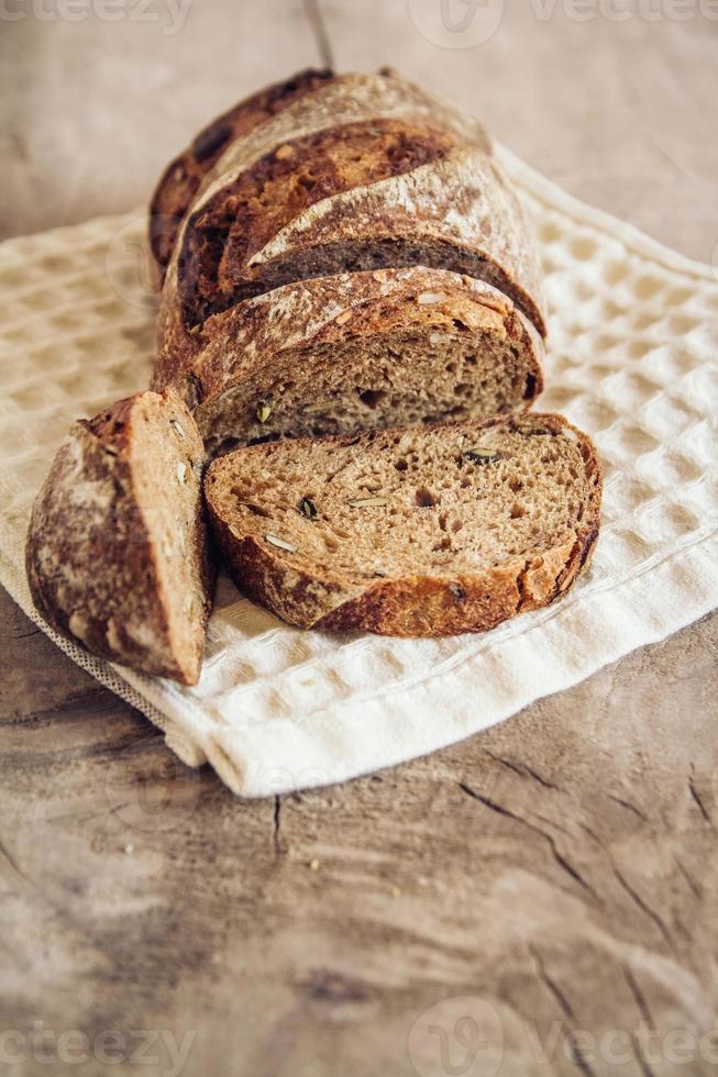 braunes frisches Brot mit Samen werden auf altem Holzhintergrund in Stücke geschnitten foto