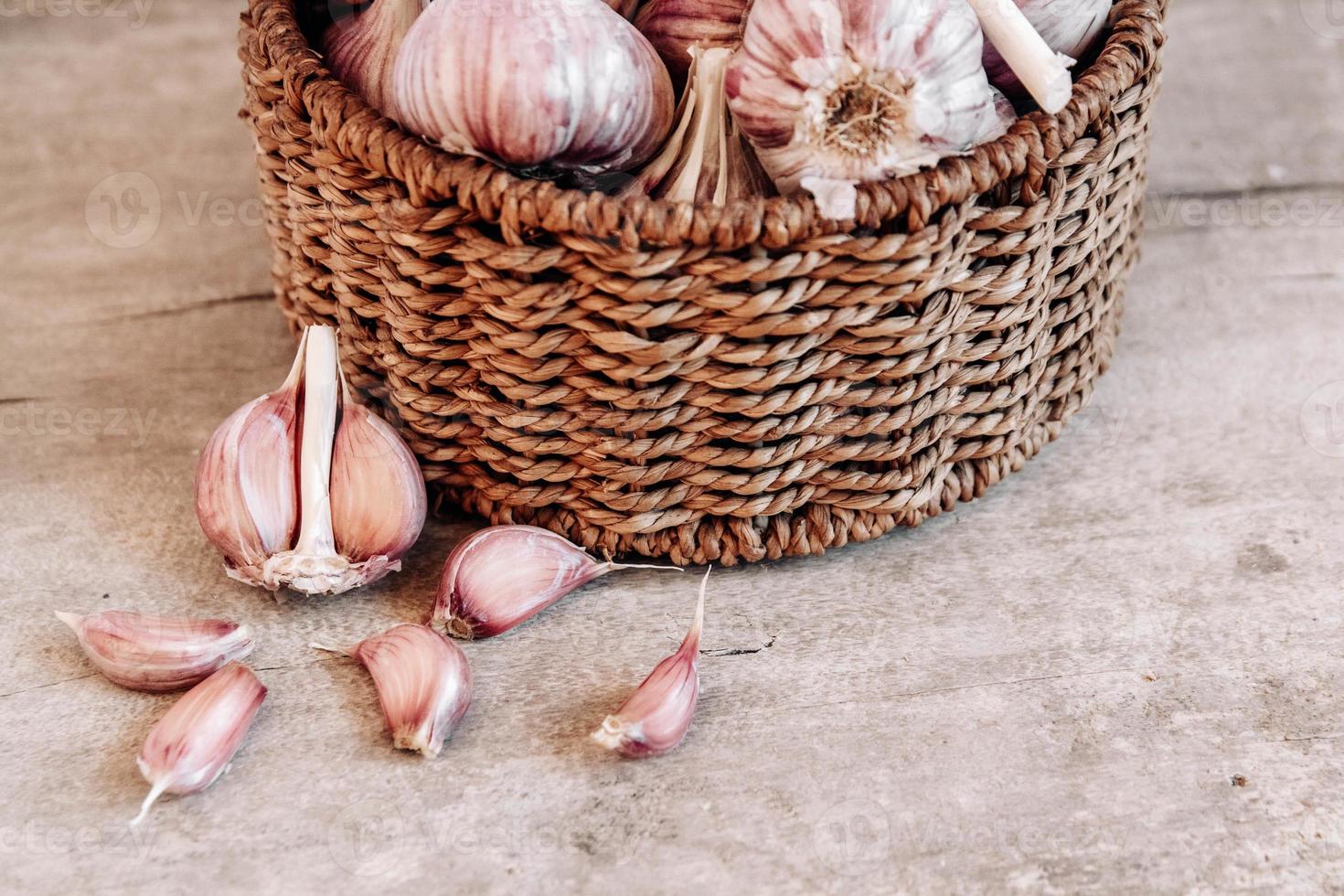 Knoblauch in einem Weidenkorb auf einem Holztischhintergrund foto